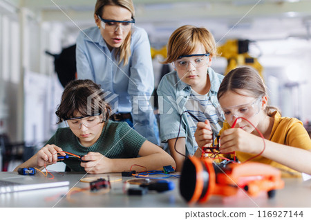 Children learning robotics in Elementary school. Young students building robot in after school robotics club. 116927144