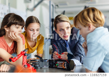 Children learning robotics in Elementary school. Young students building robot in after school robotics club. Field trip to real robotics laboratory. 116927159