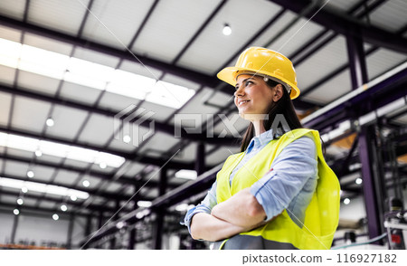 Manager woman in business casual clothes and reflective safety clothes controlling goods in warehouse. 116927182