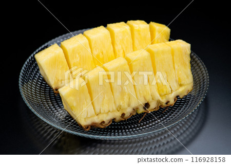Cut pineapple in a glass bowl on a black background Cut pineapple in a glass bowl on a black background 116928158