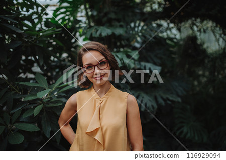 Beautiful woman standing in botanical garden, in the middle of lush green foliage. Beautiful woman standing in botanical garden, in the middle of lush green foliage. 116929094