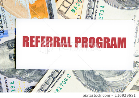 REFERRAL PROGRAM word. text written on a business card against the background of dollar bills REFERRAL PROGRAM word. text written on a business card against the background of dollar bills 116929651
