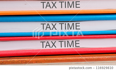 Business and tax concept. TAX TIME close-up on the ends of the notebooks Business and tax concept. TAX TIME close-up on the ends of the notebooks 116929810