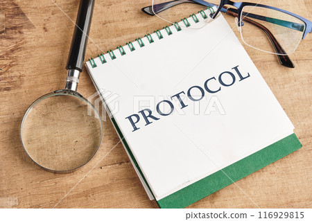 A word PROTOCOL written on a notebook in a composition with a magnifying glass, glasses and a pencil A word PROTOCOL written on a notebook in a composition with a magnifying glass, glasses and a pencil 116929815