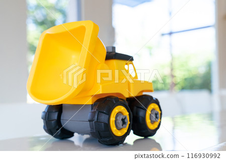Dump truck yellow construction toy vehicle with articulated parts built with sturdy plastic is placed on a table. Dump truck yellow construction toy vehicle with articulated parts built with sturdy plastic is placed on a table. 116930992