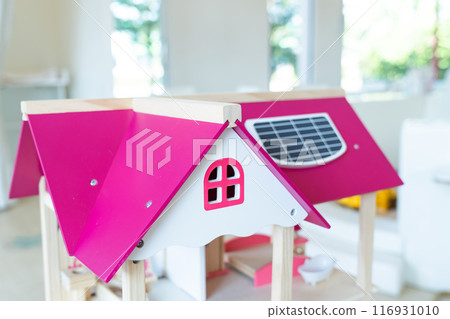 A solar cell is installed on the pink roof of a model wooden toy house. A solar cell is installed on the pink roof of a model wooden toy house. 116931010