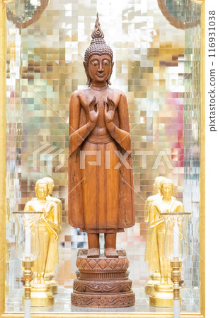 standing Buddha statue made of wood was placed between the smaller golden Buddha images of apostles. standing Buddha statue made of wood was placed between the smaller golden Buddha images of apostles. 116931038