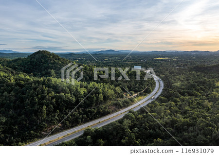 Aerial landscape of 4 lane road with residential area, forest, mountain, blue sky and sunlight with high angle view of main road from Drone shot in Tak province, northern countryside of Thailand. Aerial landscape of 4 lane road with residential area, forest, mountain, blue sky and sunlight with high angle view of main road from Drone shot in Tak province, northern countryside of Thailand. 116931079
