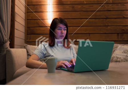 Woman Working on Laptop with Coffee in Cozy Room 116931271