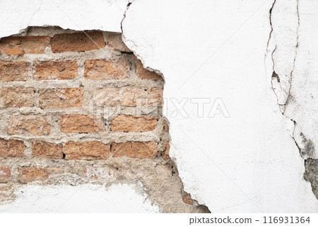 Cracked and broken white cement surface wall outside that shows the brick wall pattern inside of it Cracked and broken white cement surface wall outside that shows the brick wall pattern inside of it 116931364