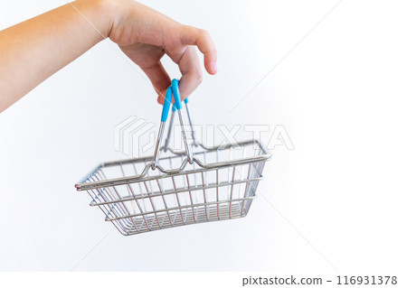 Kid hand carries Small shopping basket on white background. It is a symbol of online shopping. 116931378
