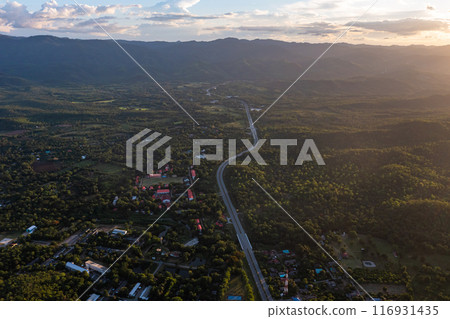 Aerial landscape of 4 lane road with residential area, forest, mountain, blue sky and sunlight with high angle view of main road from Drone shot in Tak province, northern countryside of Thailand. Aerial landscape of 4 lane road with residential area, forest, mountain, blue sky and sunlight with high angle view of main road from Drone shot in Tak province, northern countryside of Thailand. 116931435