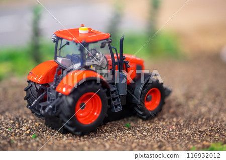 Orange toy tractor laying on the ground in the garden where the background was blurred. 116932012