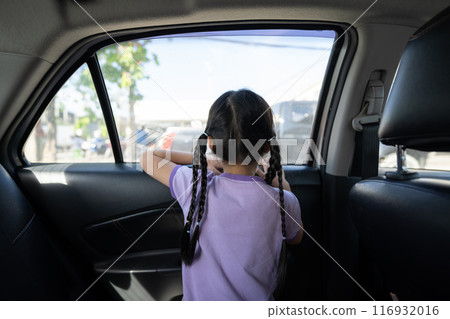 Backside of Little Asian 5 years old girl, is looking to the outside through car window mirror in the afternoon time. 116932016