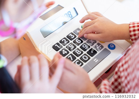 Kids are playing a wooden toy cash register by pressing the number seven, and others on it, respectively. 116932032