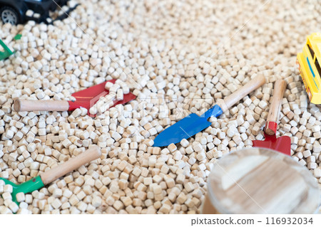 Yellow construction toy vehicles and Dinosaurs Toys are placed in kids playground filled with wooden cubes around it. 116932034