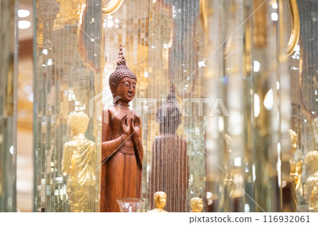 standing Buddha statue made of wood was placed between the smaller golden Buddha images of apostles. 116932061