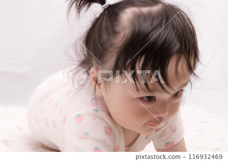 [A baby with tied hair starting to crawl] 116932469