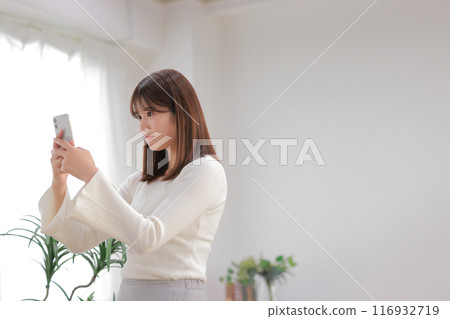 Young woman looking at SNS with wide eyes 1 116932719
