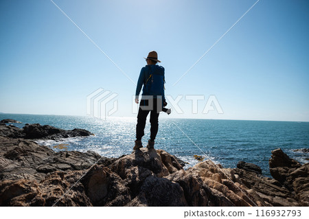 Woman photographer enjoy the view on sunrise seaside rocks 116932793