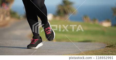 Young fitness woman legs, running in the city public park in morning 116932991