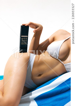Time for relaxation. Cropped Image for tanned, skin, attractive female body in swimsuit lying on beach towel with vintage wireless phone. 116933327