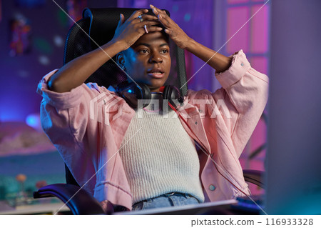 Portrait of frustrated African American woman watching videos or gaming at night at home 116933328