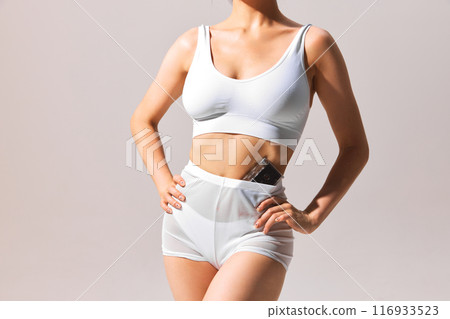 Cropped image of slim female body, model posing in underwear with vintage cassette on grey background. 116933523