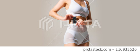 Cropped image of female slim body, model posing in white underwear with retro cassette again grey background. Banner Cropped image of female slim body, model posing in white underwear with retro cassette again grey background. Banner 116933526