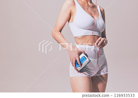 Cropped image of young woman with slim body, wearing white underwear, holding vintage cassette music player and headphones Cropped image of young woman with slim body, wearing white underwear, holding vintage cassette music player and headphones 116933533
