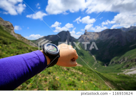 Hiker on high altitude mountain top checking the altimeter on the sports watch 116933624