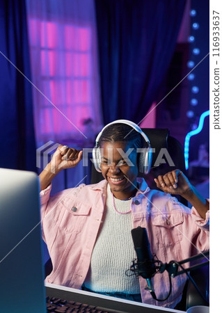 Vertical portrait of excited girl gamer cheering and celebrating victory while playing videogames at home copy space Vertical portrait of excited girl gamer cheering and celebrating victory while playing videogames at home copy space 116933637
