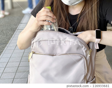 一名婦女將塑膠瓶放入包包中 116933681