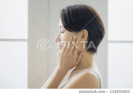 Middle-aged woman looking in the mirror in the living room 116935003