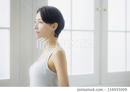 Middle-aged woman looking in the mirror in the living room 116935009