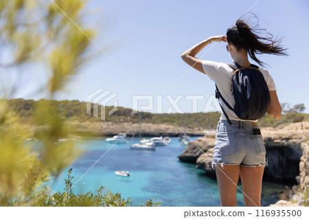 A young woman watching the surface of the sea. The concept of active travel. A young woman watching the surface of the sea. The concept of active travel. 116935500