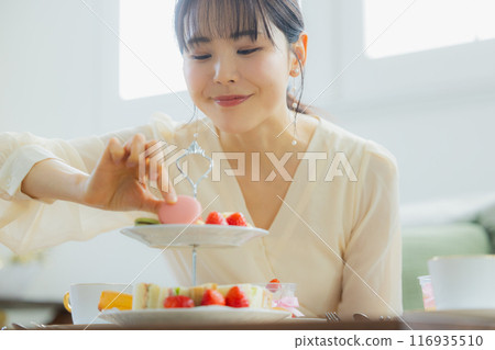 A woman eating sweets at a cafe 116935510
