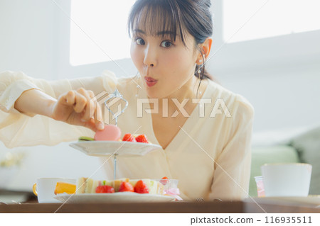 A woman eating sweets at a cafe 116935511