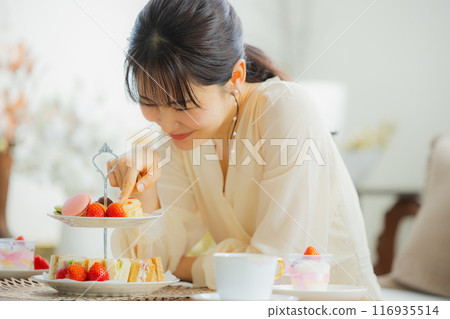 A woman eating sweets at a cafe 116935514