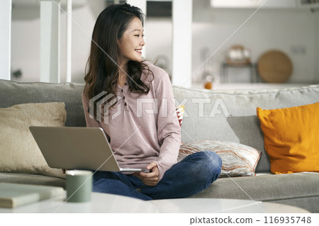 happy young asian woman with laptop computer at home 116935748