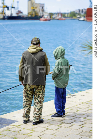 Retired elderly man goes fishing with his grandson from pier. Family active lifestyle 116936193