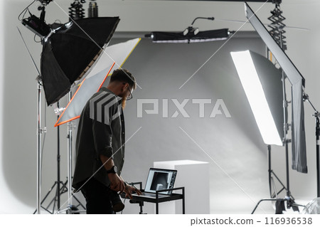 Photographer adjusting camera settings in professional studio with advanced lighting setup Photographer adjusting camera settings in professional studio with advanced lighting setup 116936538