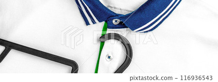 A neatly ironed white polo shirt with a blue striped collar and a black hanger lying on top. Comfortable fashionable casual wear. Web banner design element A neatly ironed white polo shirt with a blue striped collar and a black hanger lying on top. Comfortable fashionable casual wear. Web banner design element 116936543