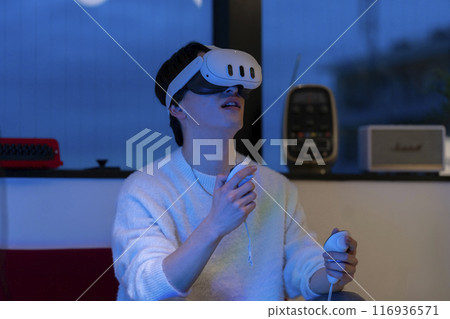 Virtual reality: A young man holding a hand controller and wearing VR goggles Virtual reality: A young man holding a hand controller and wearing VR goggles 116936571