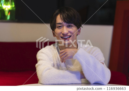 Smiling young man looking at the camera, home, night image 116936663