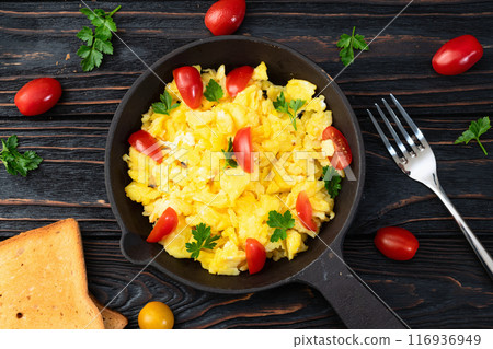Healthy vegetarian breakfast . Scrambled eggs in pan with cherry tomatoes and parsley 116936949