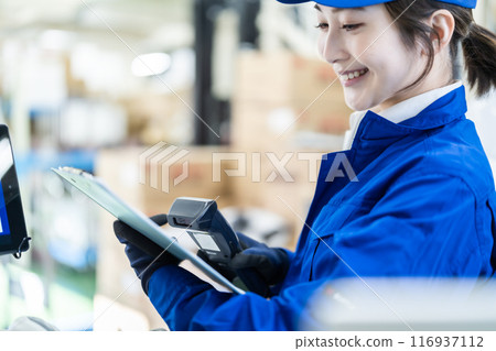 A female worker working in a logistics warehouse with a scanner in one hand 116937112