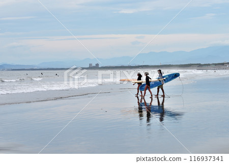 Three surfers at Katase Nishihama Beach at low tide 116937341