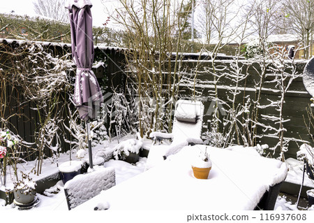 Winter snow-covered garden with garden furniture under the snow. 116937608