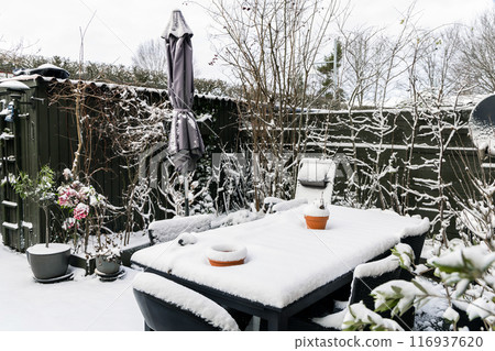 Winter snow-covered garden with garden furniture under the snow. Winter snow-covered garden with garden furniture under the snow. 116937620